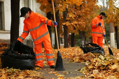 Photo of Workers cleaning street from fallen leaves on autumn day