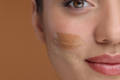 Photo of Woman with swatches of foundation on face against brown background, closeup