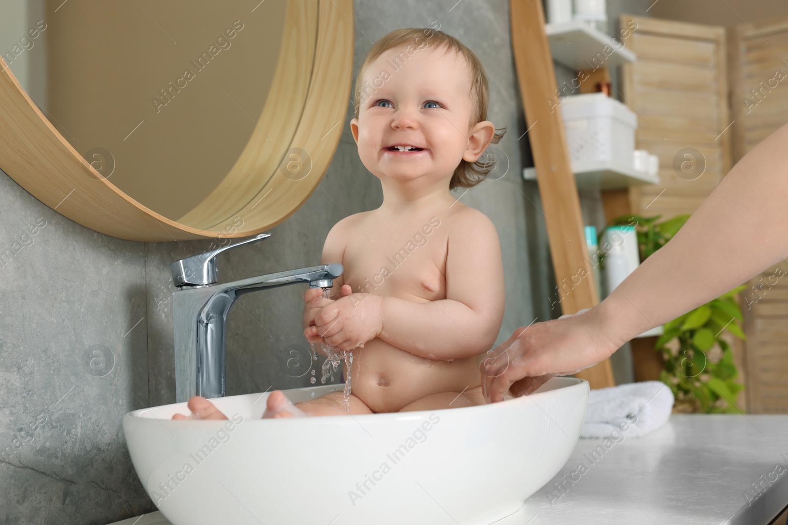 Photo of Mother washing her little baby in sink at home