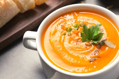 Photo of Bowl with tasty pumpkin soup served on table, closeup