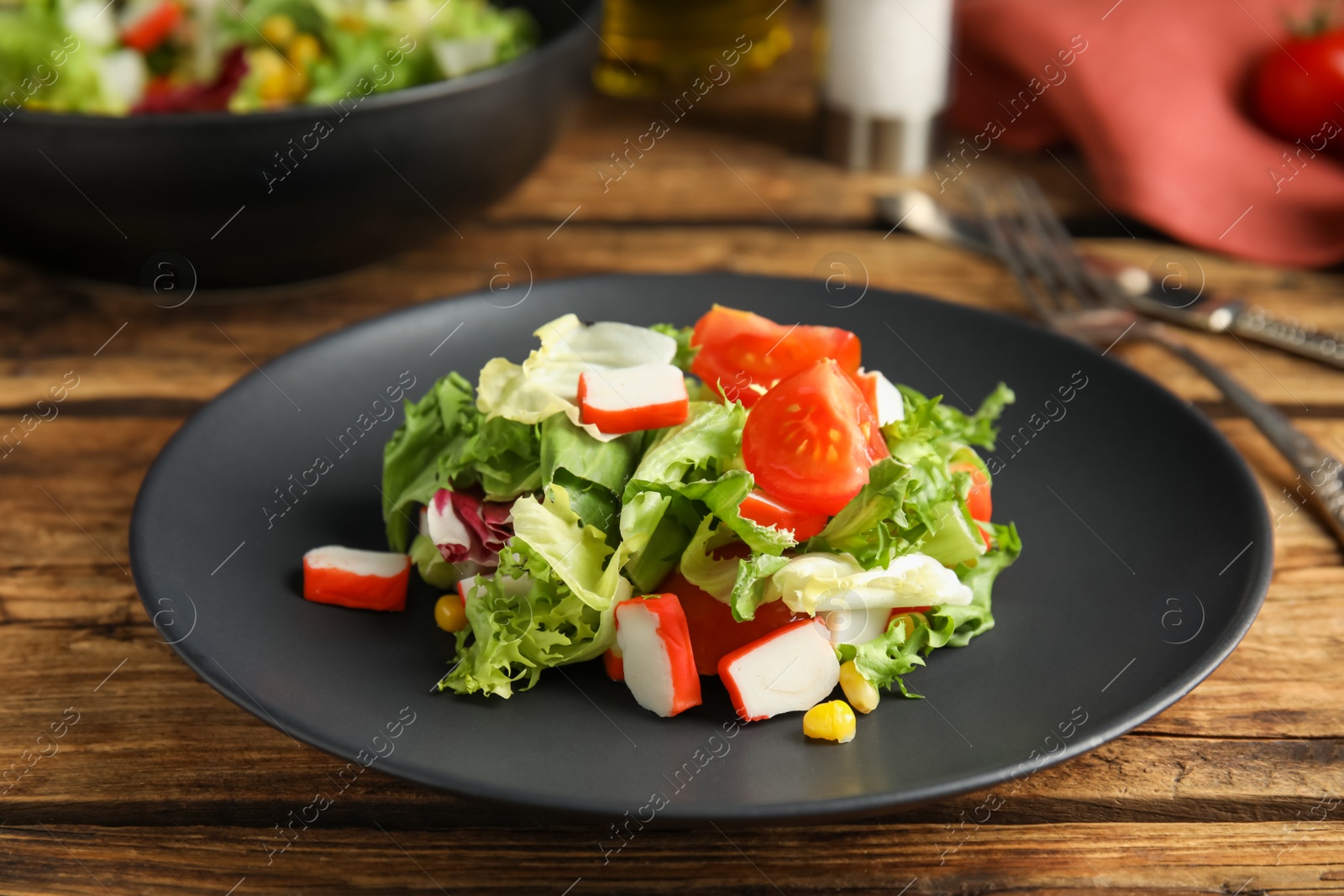 Photo of Delicious salad with crab sticks and lettuce on wooden table