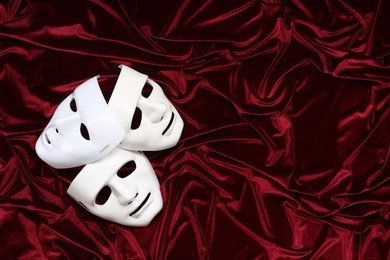 Theater arts. White masks on red fabric, top view. Space for text