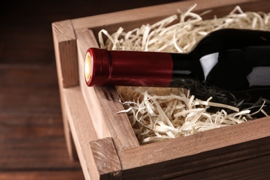 Photo of Open wooden crate with bottle of wine, closeup