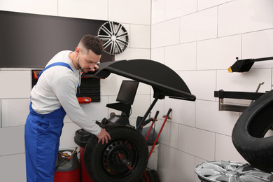 Mechanic working with wheel balancing machine at tire service