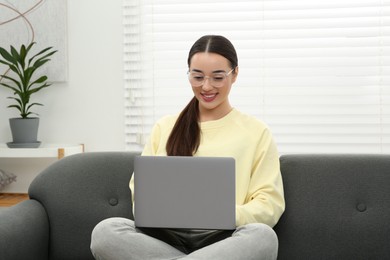 Woman using laptop on couch at home