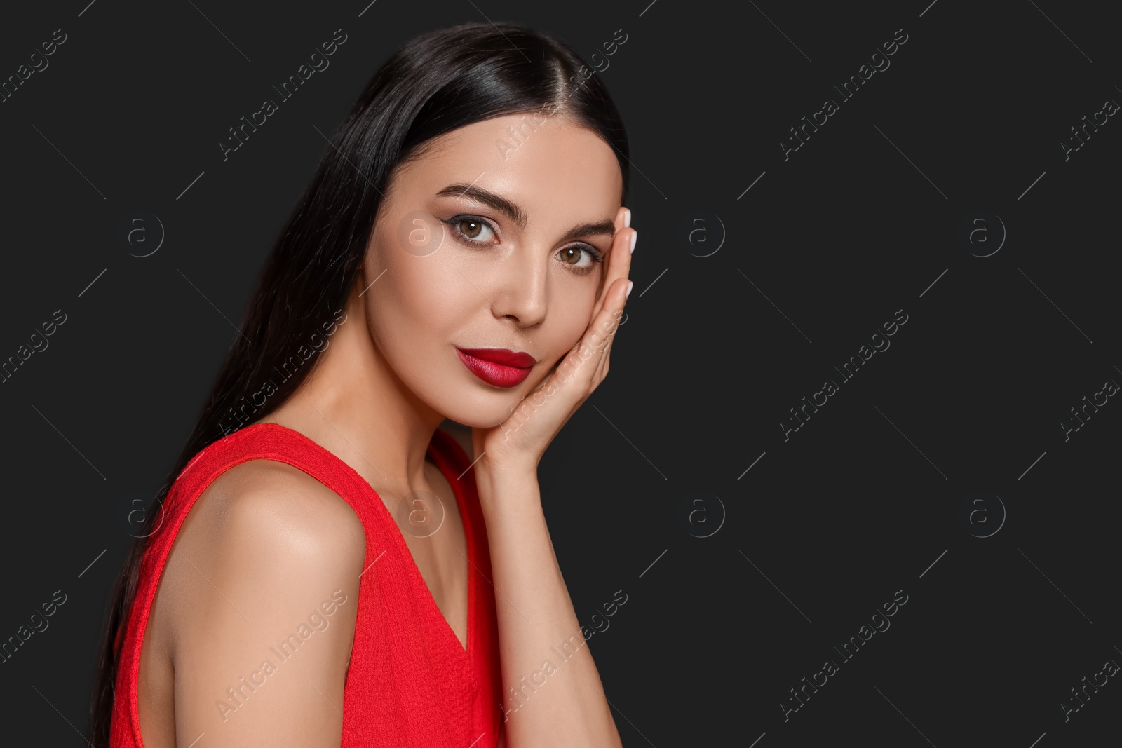 Photo of Portrait of young woman wearing beautiful red lipstick on black background, space for text