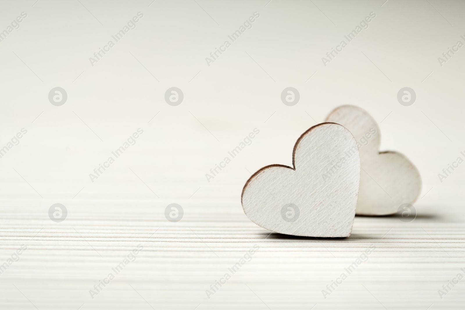 Photo of Decorative hearts on white wooden table, closeup with space for text. Valentine's day