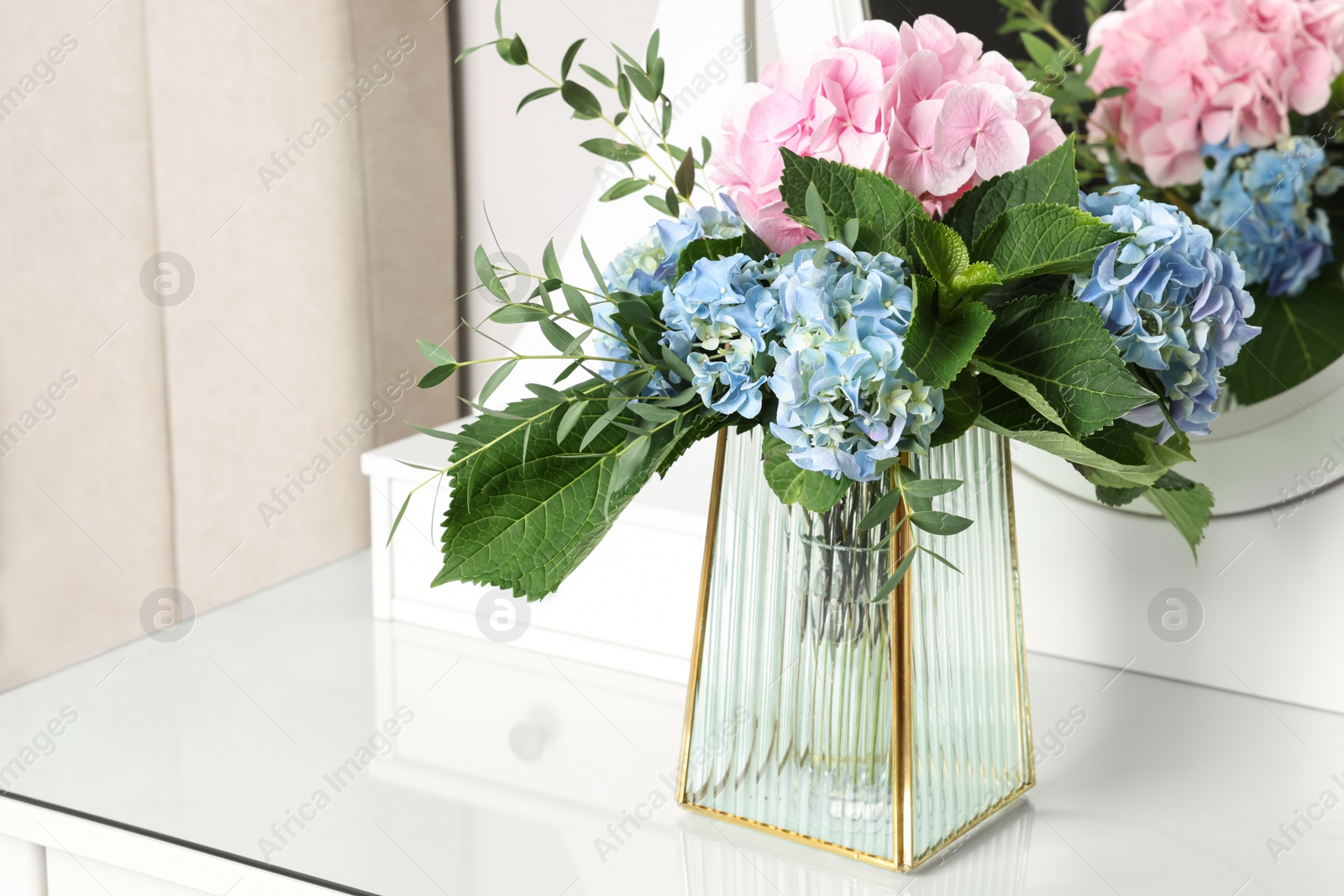 Photo of Beautiful hortensia flowers in vase on dressing table indoors. Space for text