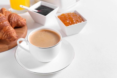 Photo of Breakfast time. Fresh croissants, jams and coffee on white table. Space for text