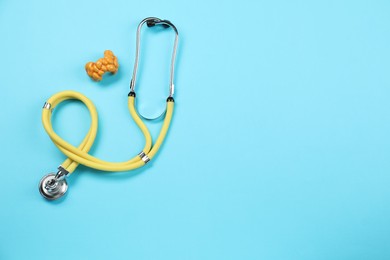 Photo of Endocrinology. Stethoscope and model of thyroid gland on light blue background, top view. Space for text