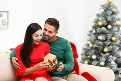 Photo of Happy young couple with Christmas gift at home