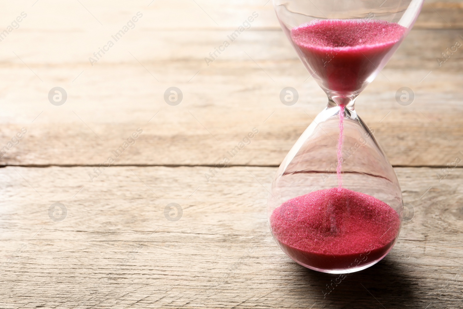 Photo of Hourglass with flowing sand on table. Time management