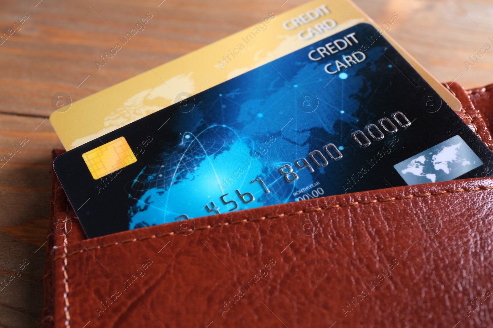 Photo of Credit cards in leather wallet on wooden table, closeup