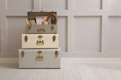 Storage trunks with different decor elements near light wall indoors, space for text. Interior design