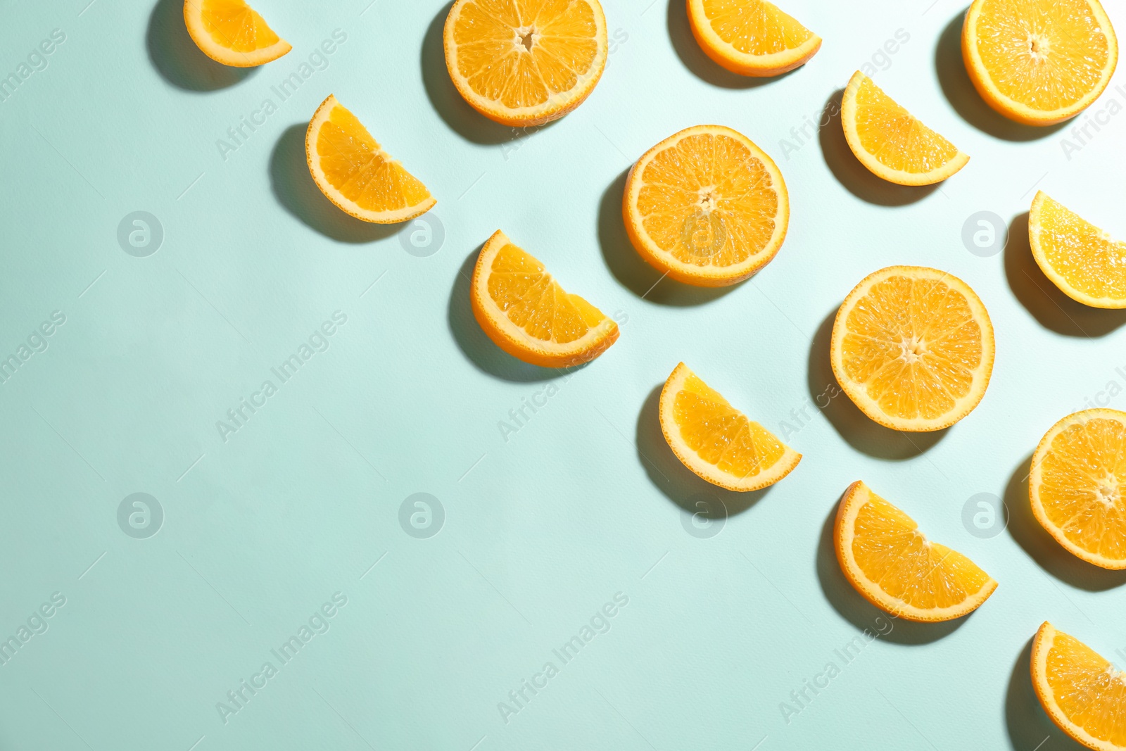 Photo of Cut fresh ripe oranges on light blue background, flat lay. Space for text