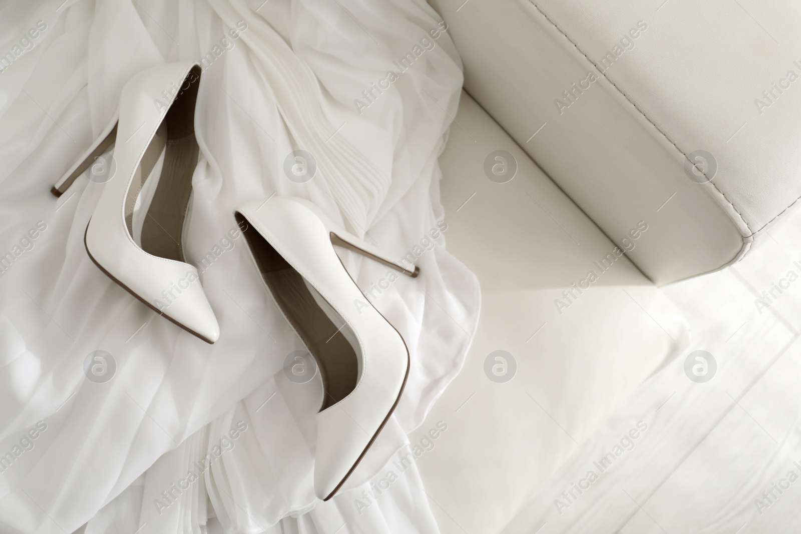 Photo of White wedding shoes on sofa, above view