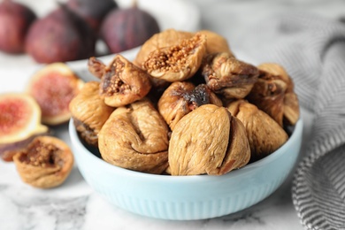 Bowl of tasty dried figs on marble table, closeup