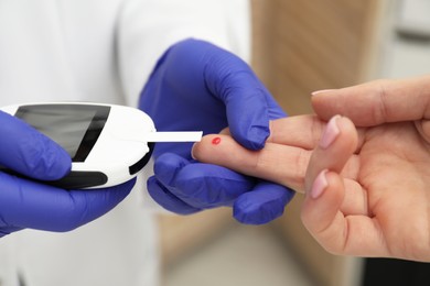Diabetes. Doctor checking patient's blood sugar level with glucometer in clinic, closeup