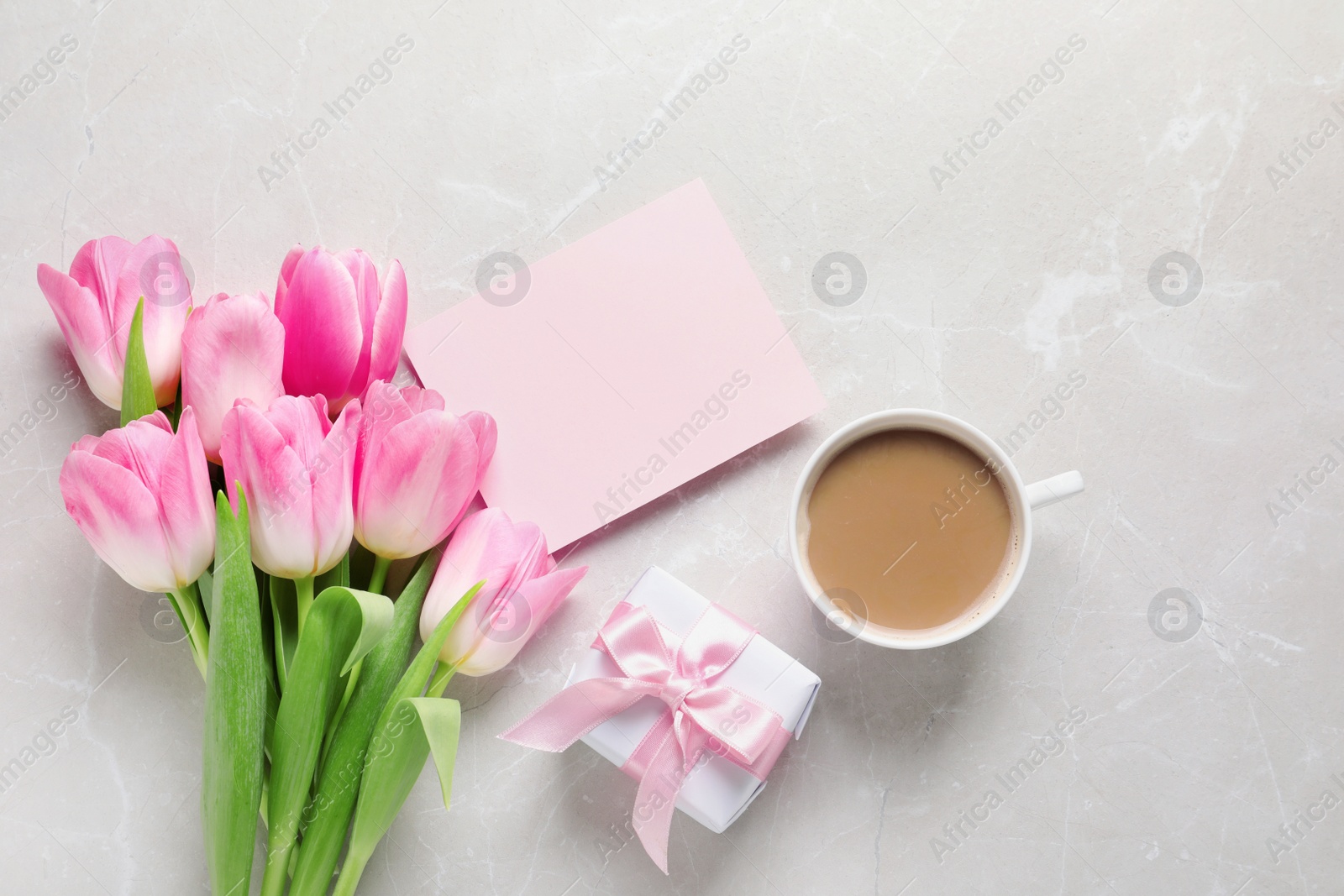 Photo of Flat lay composition of tulips and blank card on marble background, space for text. International Women's Day