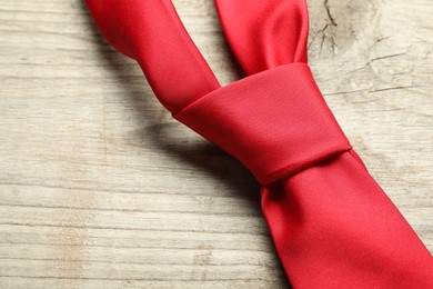 One red necktie on light wooden table, top view. Space for text