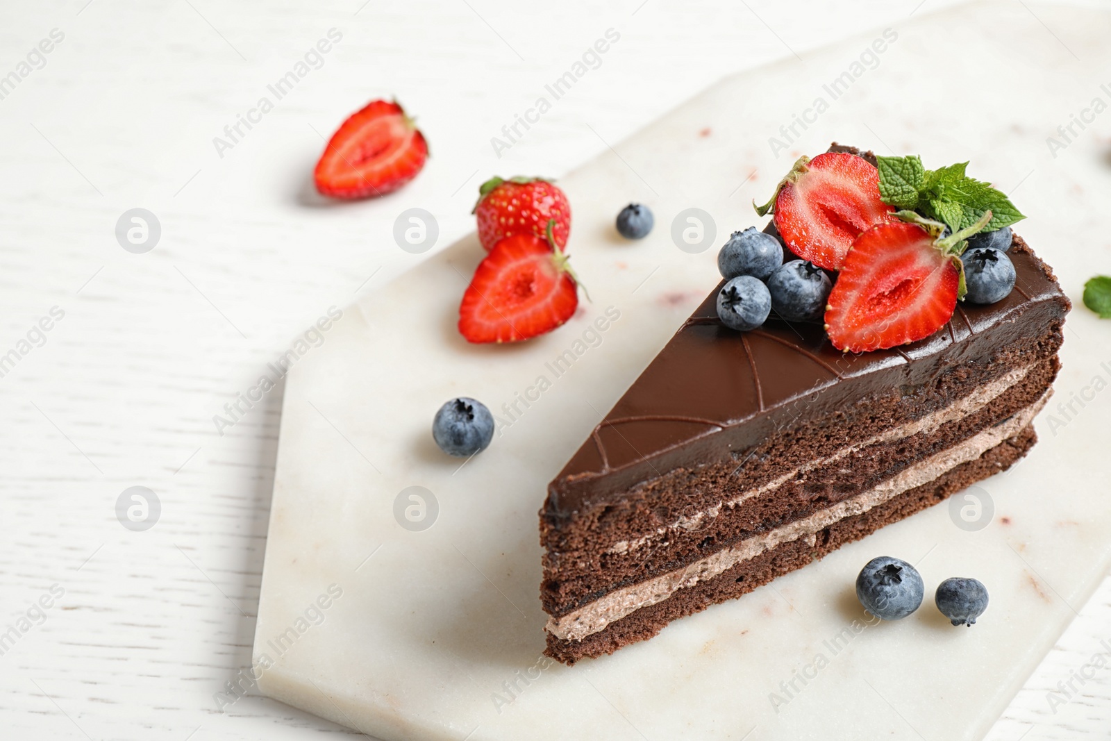 Photo of Delicious fresh chocolate cake with berries on white table