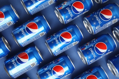 Photo of MYKOLAIV, UKRAINE - FEBRUARY 08, 2021: Cans of Pepsi on blue background, flat lay