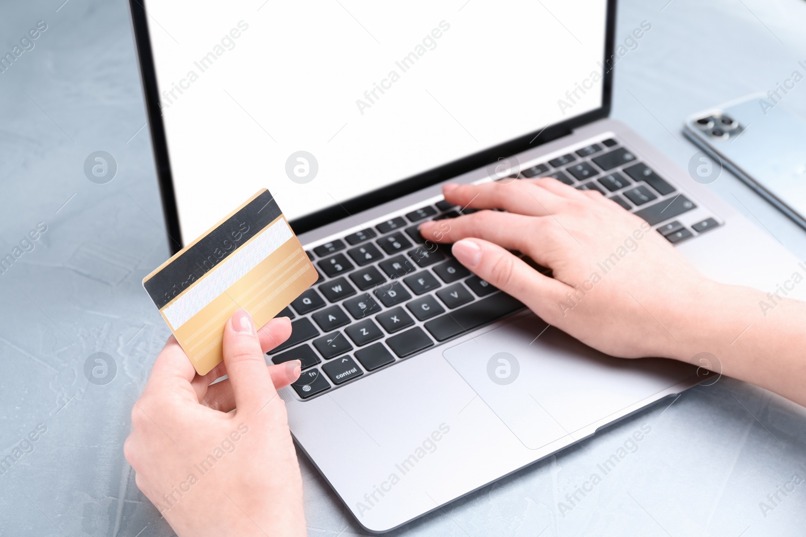 Photo of Online payment. Woman with laptop and credit card at white table, closeup