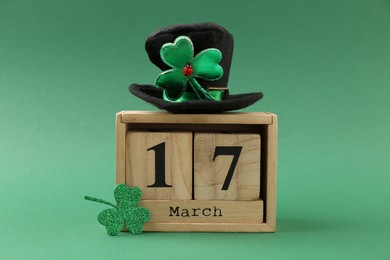 Photo of St. Patrick's day - 17th of March. Block calendar, leprechaun hat and decorative clover leaf on green background
