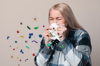 Sick mature woman on beige background. Microbes spreading