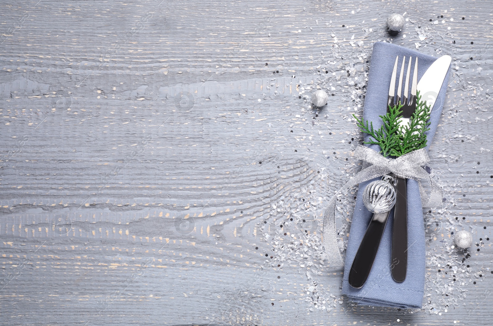 Photo of Cutlery set on grey wooden table, top view with space for text. Christmas celebration