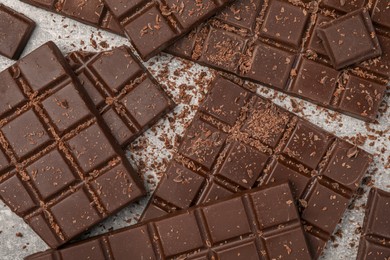 Pieces and shavings of tasty chocolate bars on light grey table, flat lay