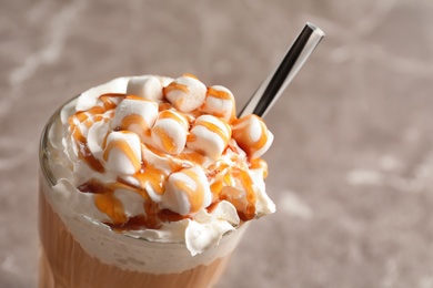 Photo of Glass with delicious caramel frappe on grey background, closeup