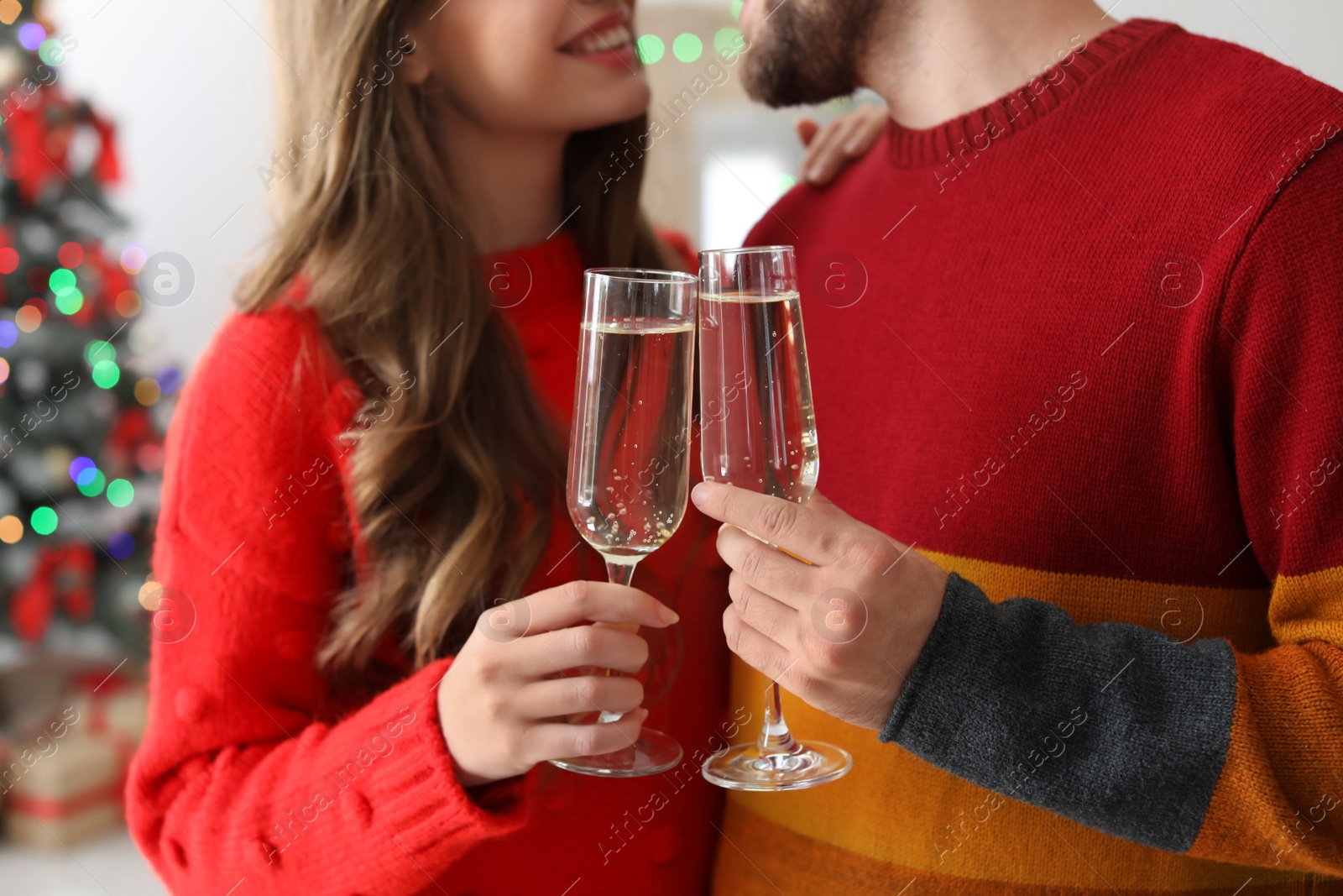 Photo of Happy young couple with glasses of champagne celebrating Christmas at home