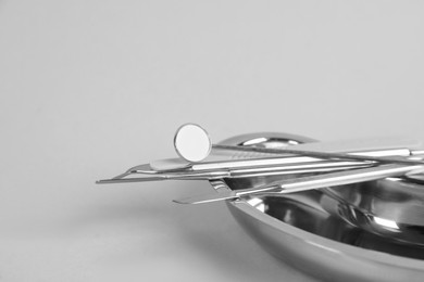 Photo of Kidney shaped tray with dentist's tools on light grey background, closeup. Space for text