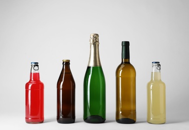 Photo of Bottles with different alcoholic drinks on light background