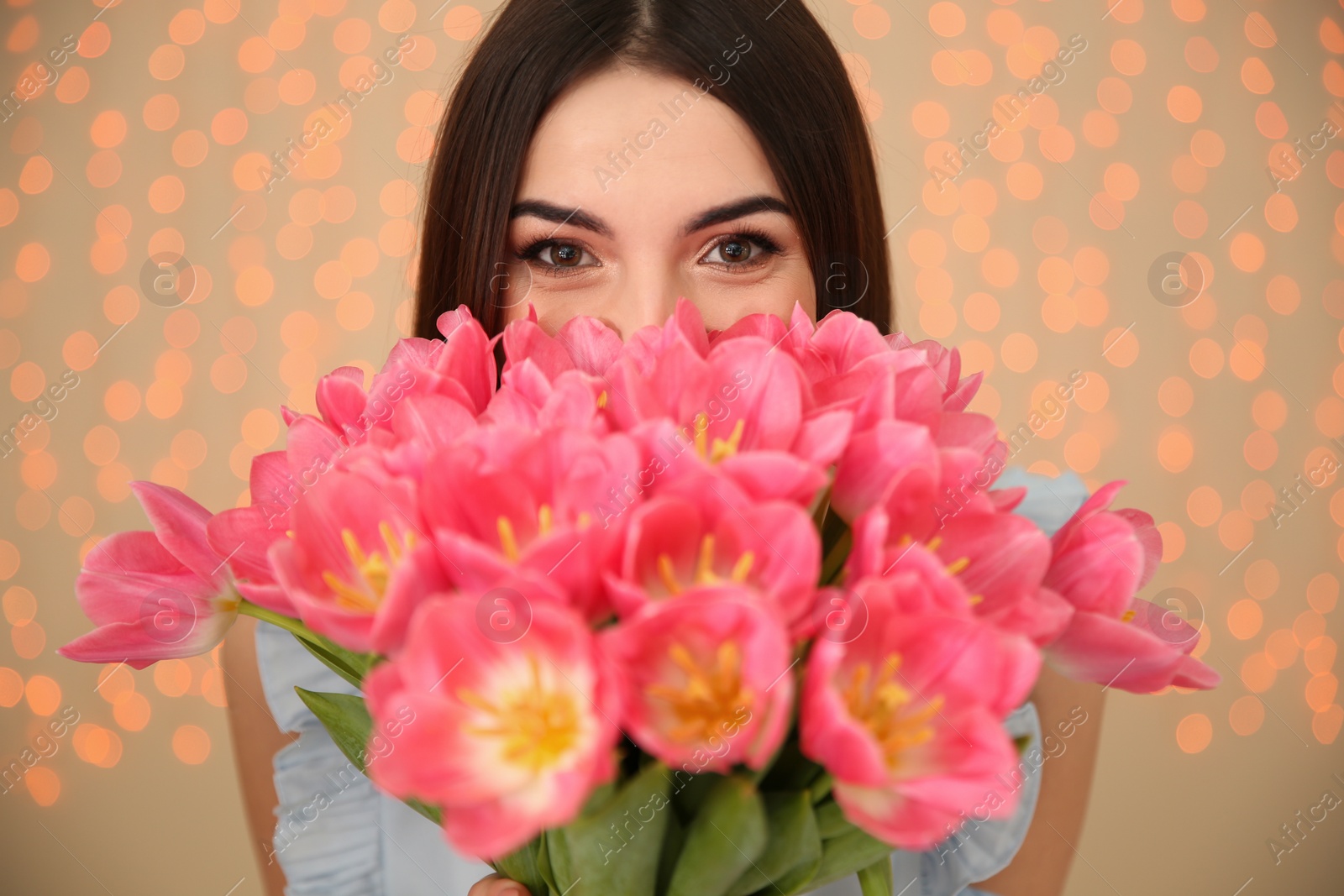 Photo of Beautiful girl with spring tulips on blurred background, closeup. International Women's Day