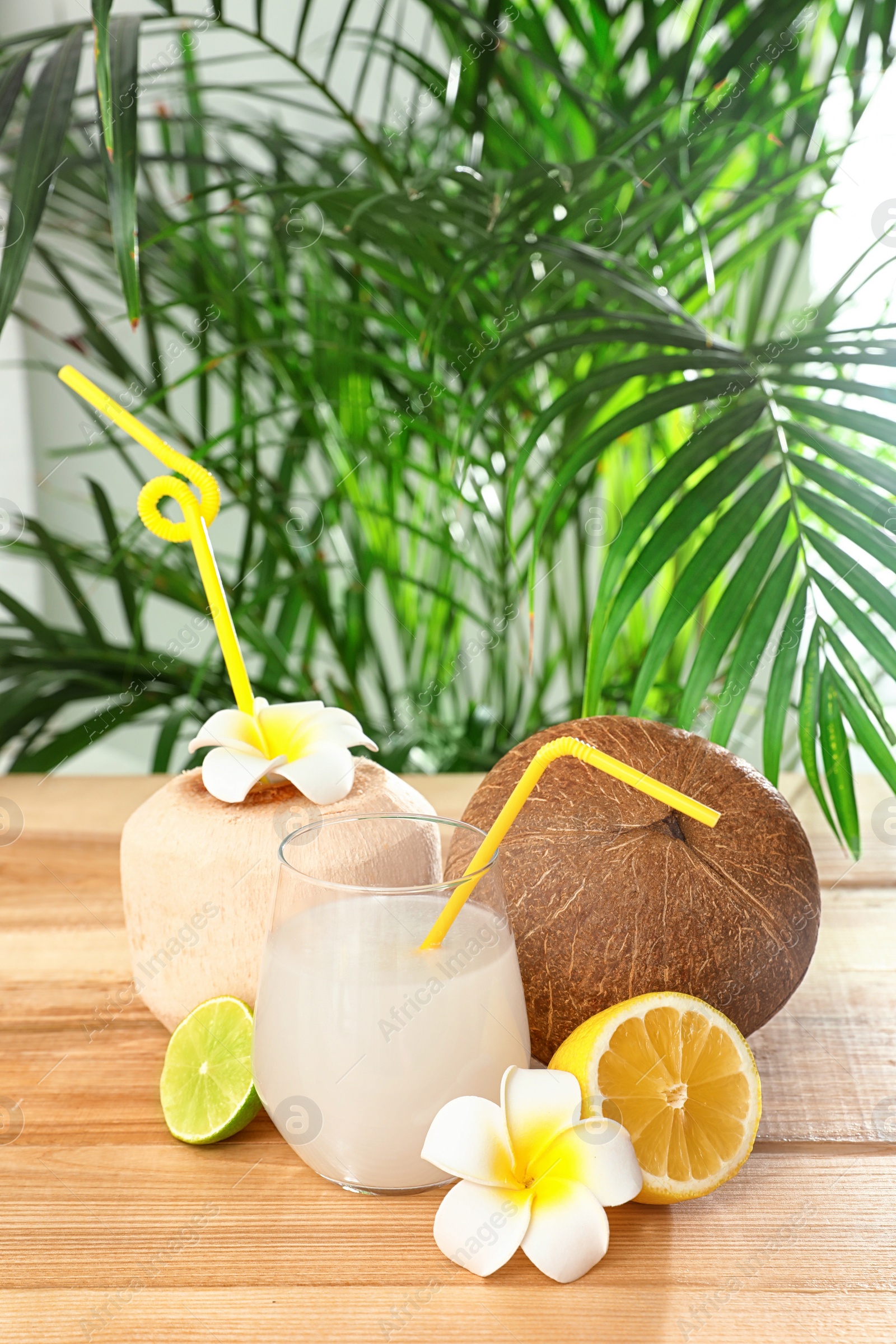 Photo of Composition with glass of coconut water on wooden table against blurred background