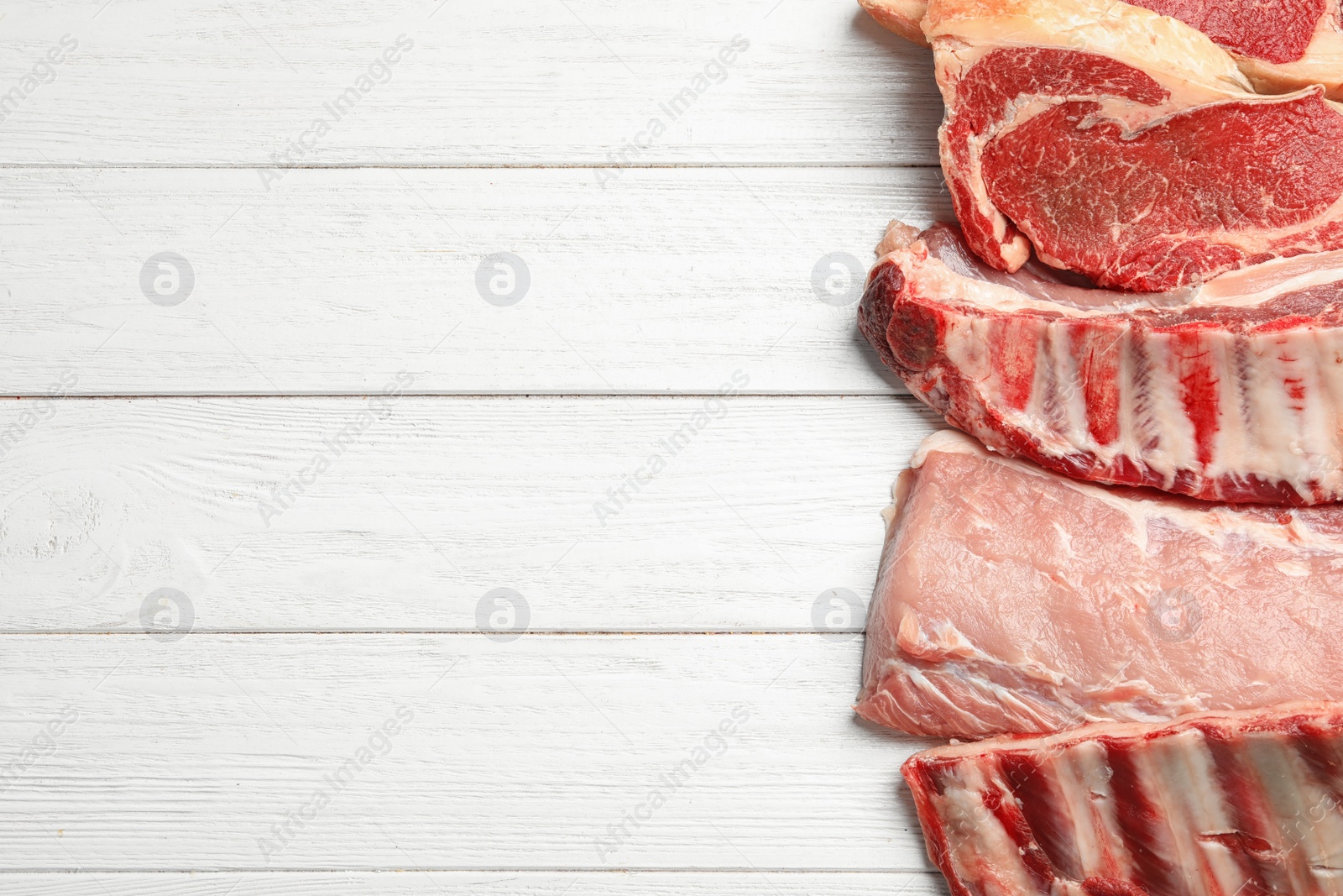 Photo of Different types of meat on white wooden table, flat lay. Space for text