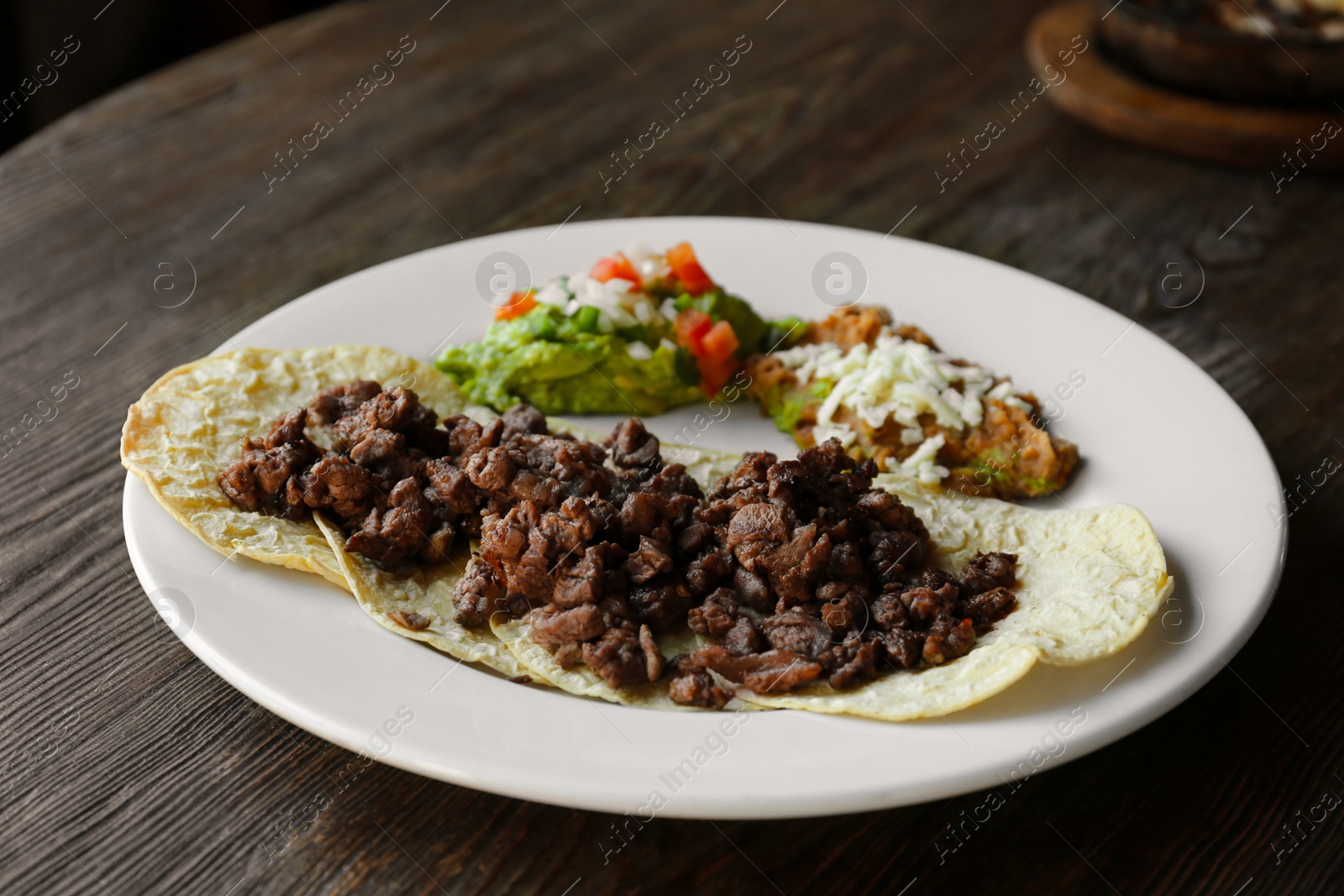 Photo of Plate with delicious tacos served on wooden table