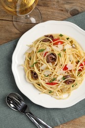 Delicious pasta with anchovies, tomatoes and parmesan cheese served on wooden table, flat lay