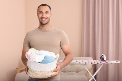 Photo of Happy man with basket full of laundry at home