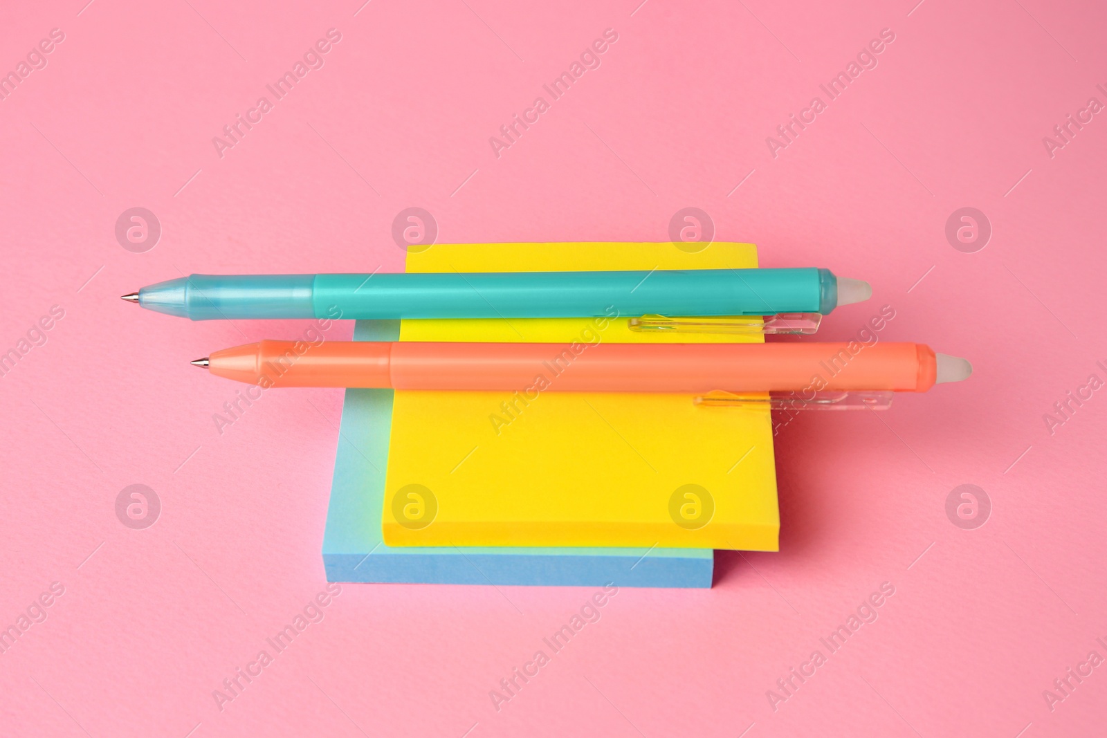 Photo of Colorful paper notes with erasable pens on pink background, closeup