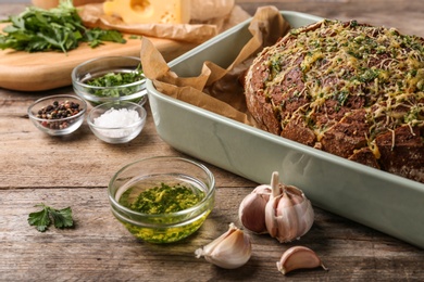 Photo of Tasty homemade garlic bread with cheese and herbs on wooden table