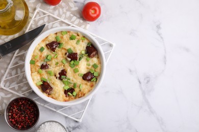 Photo of Tasty sausage casserole in baking dish, knife and ingredients on white marble table, flat lay. Space for text