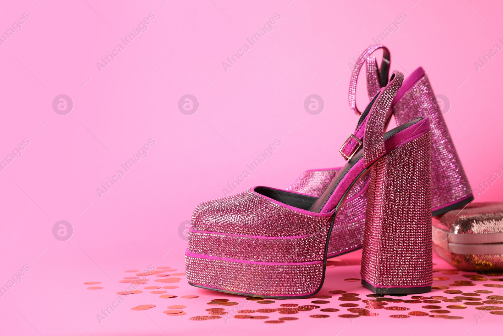 Photo of Fashionable punk square toe ankle strap pumps and confetti on pink background, space for text. Shiny party platform high heeled shoes