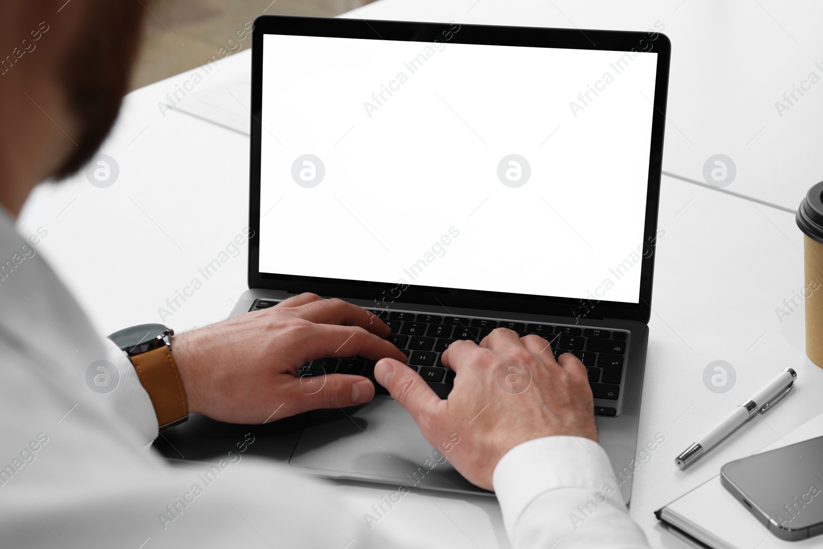 Photo of Man working on laptop at white desk in office, closeup