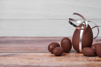 Photo of Whole delicious chocolate eggs on wooden table. Space for text