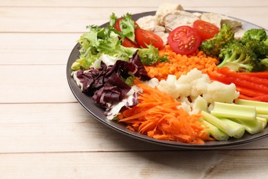 Photo of Balanced diet and healthy foods. Plate with different delicious products on light wooden table, closeup