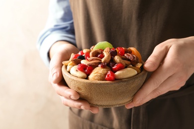 Photo of Young woman holding bowl with different dried fruits and nuts, closeup