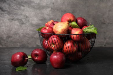 Photo of Fresh ripe red apples with water drops in metal bowl on dark grey table